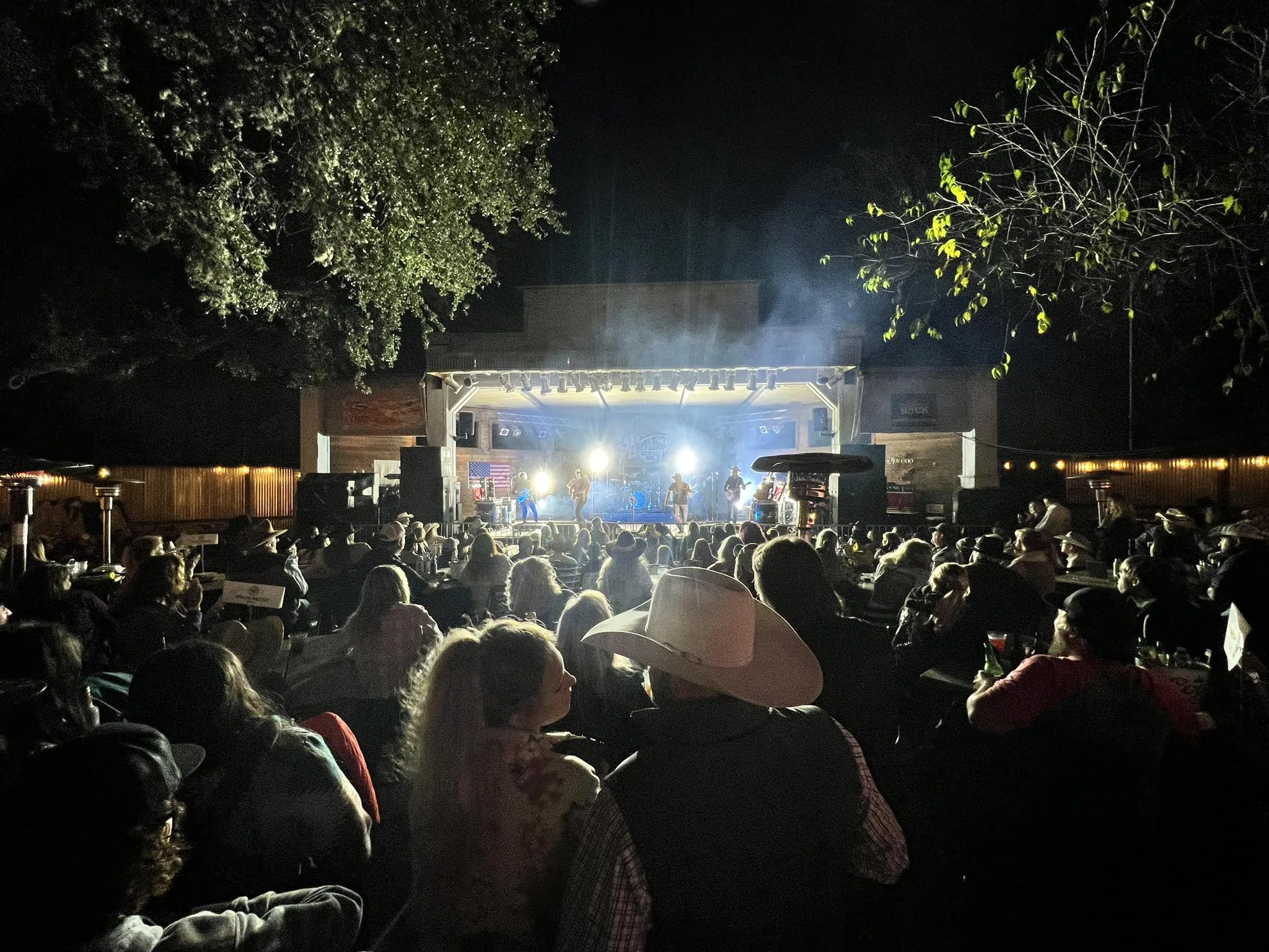 Outdoor seating and stage under string lights at the 11th Street Cowboy Bar in Bandera