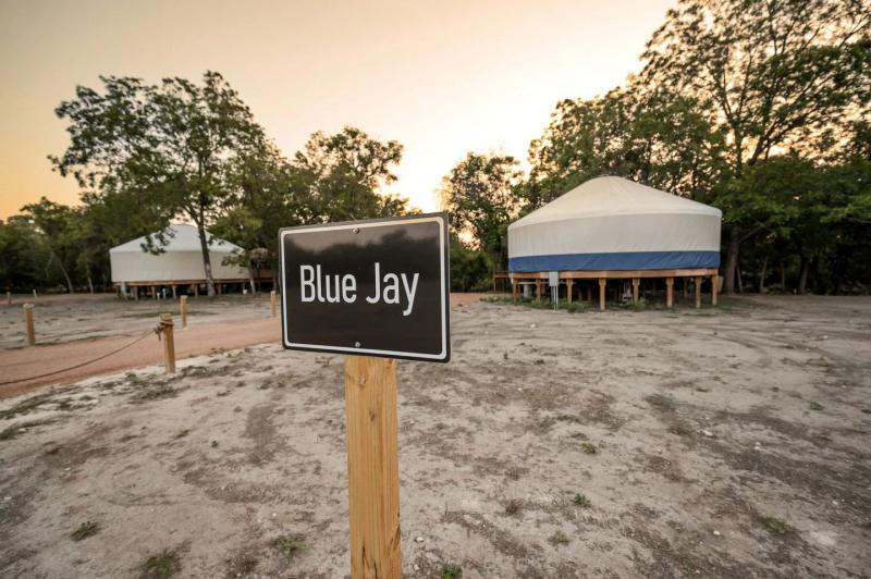 Blue Jay Yurt — entrance sign with the canvas yurt and gazebo at sunset.