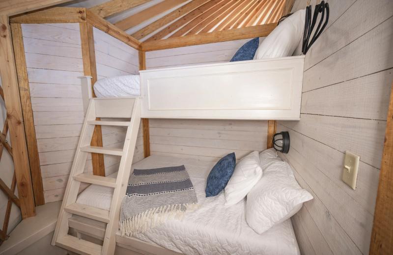 Blue Jay Yurt — built-in twin bunk beds with white and navy bedding.