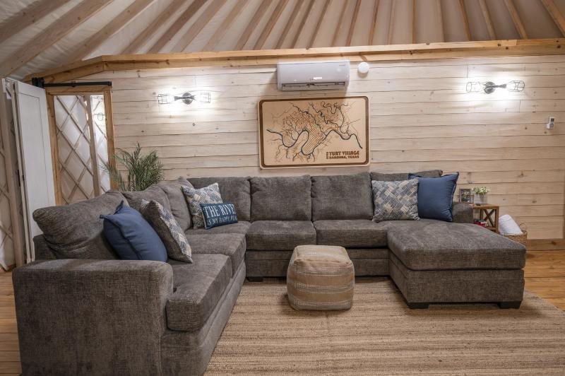 Blue Jay Yurt — living area with a charcoal sectional and rustic wood walls.