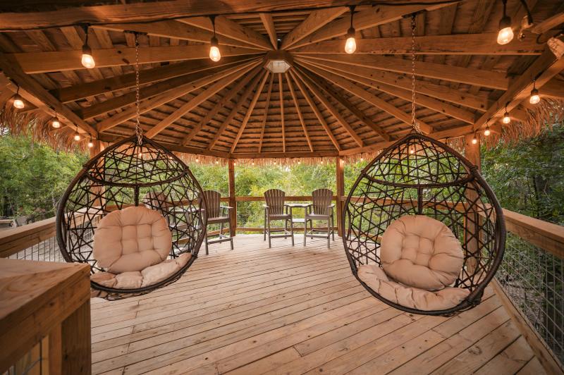 Blue Jay Yurt — pair of hanging chairs inside the lighted thatched gazebo.