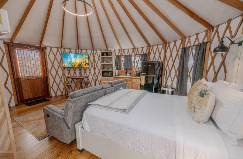 Canary Yurt — queen bed and loveseat in the open-plan interior.