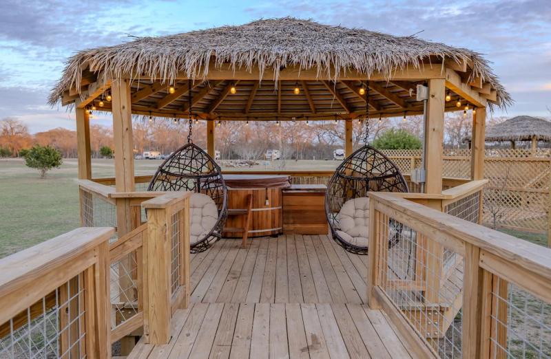 Canary Yurt — thatched gazebo with hanging chairs and warm string lights.