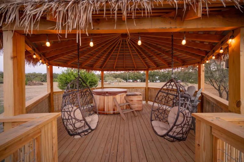 Cockatoo Yurt — private thatched gazebo with hanging chairs and string lights.