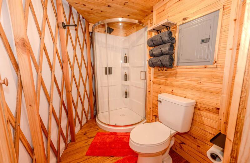 Cockatoo Yurt — private bathroom with curved glass shower and wood-paneled walls.