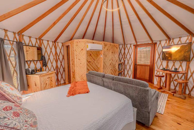 Cockatoo Yurt — queen bed and loveseat in the open-plan interior.
