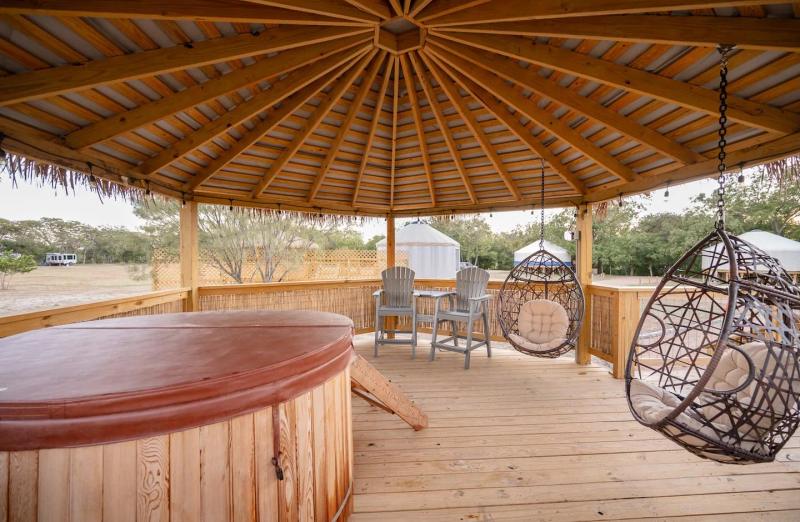 Cockatoo Yurt — cedar hot tub and two hanging egg chairs on the gazebo deck overlooking the yurt village.
