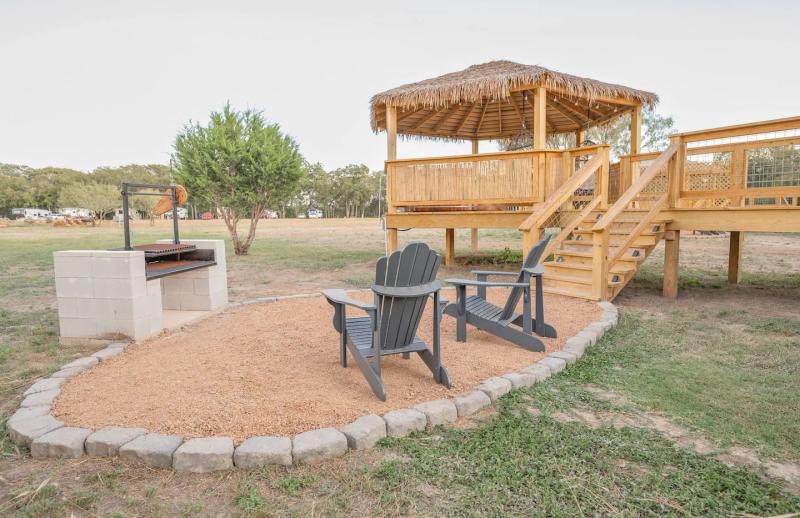 Cockatoo Yurt — Adirondack chairs and masonry fire pit beside the raised gazebo.