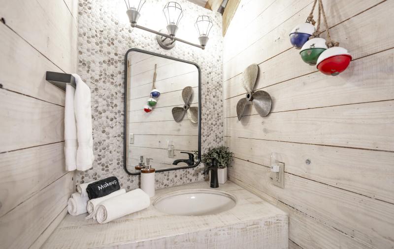 Hoot Owl Yurt — powder room with pebble-tile wall, boat-buoy pendant lights and propeller decor.