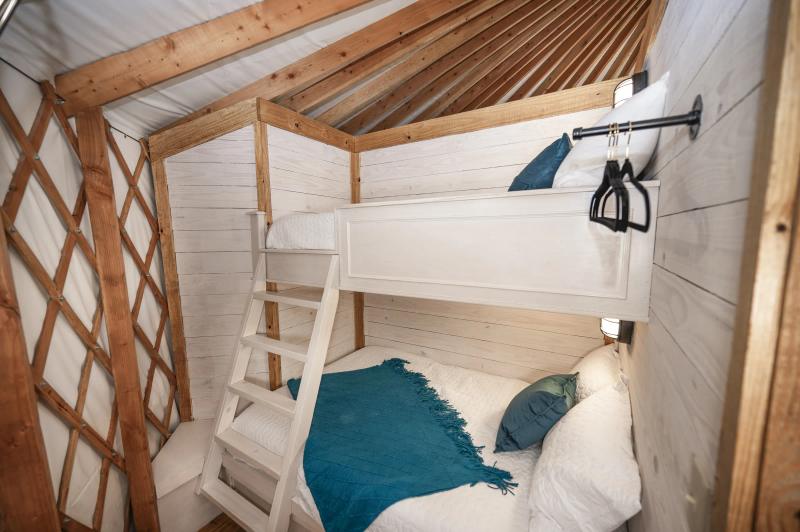 Hoot Owl Yurt — built-in twin bunk beds with teal and white bedding.