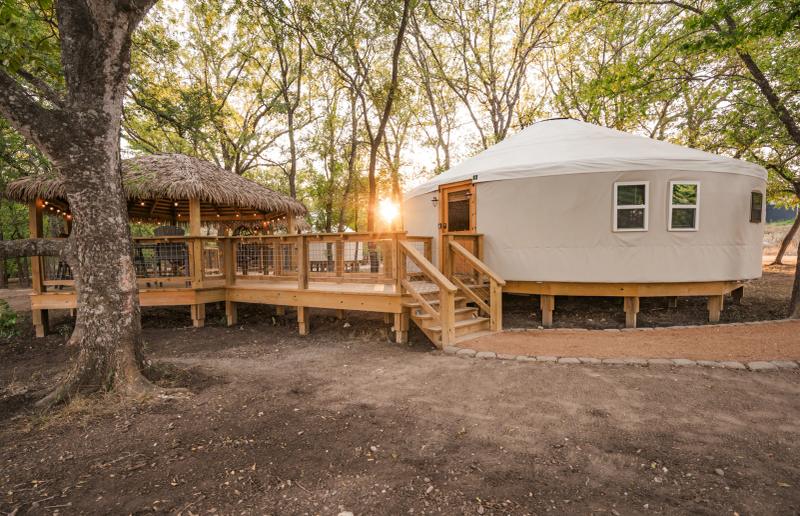 Hoot Owl Yurt — canvas yurt and connected thatched gazebo among mature trees.