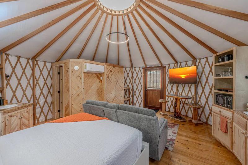King Fisher Yurt — queen bed, loveseat, and television in the open-plan interior.