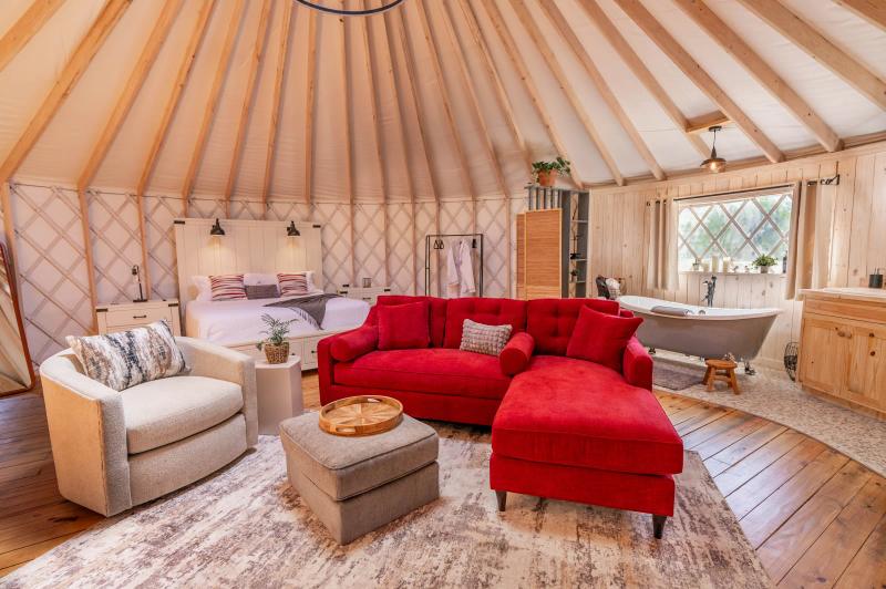 Love Bird Yurt — red sectional, armchair and clawfoot soaking tub in the honeymoon interior.