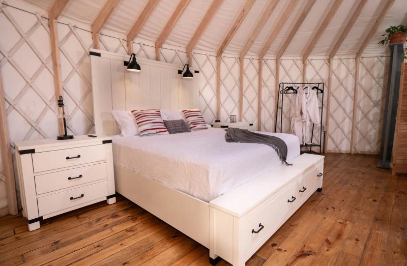Love Bird Yurt — king bed and bedside lighting beneath the pale canvas ceiling.