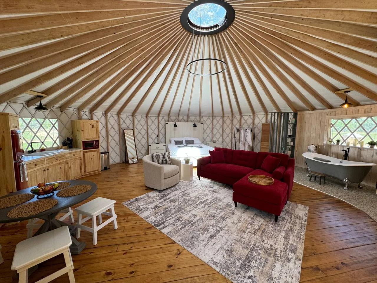 Love Bird Yurt — spacious honeymoon interior with red sofa, soaking tub, and clear sky dome.