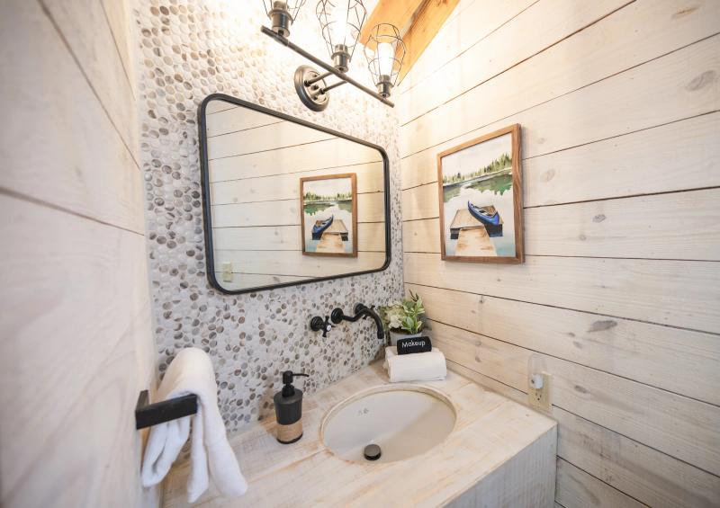 Mockingbird Yurt — private vanity with patterned tile, framed art, and fresh towels.
