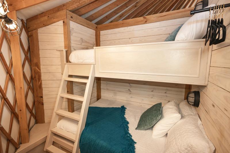 Mockingbird Yurt — built-in twin bunk beds with teal and white bedding.