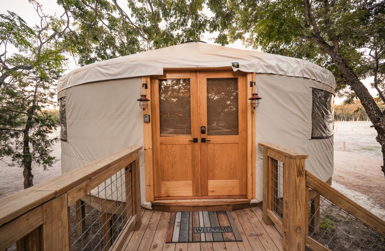 Mockingbird Yurt — cedar entry deck and glass double doors framed by oaks at dawn.