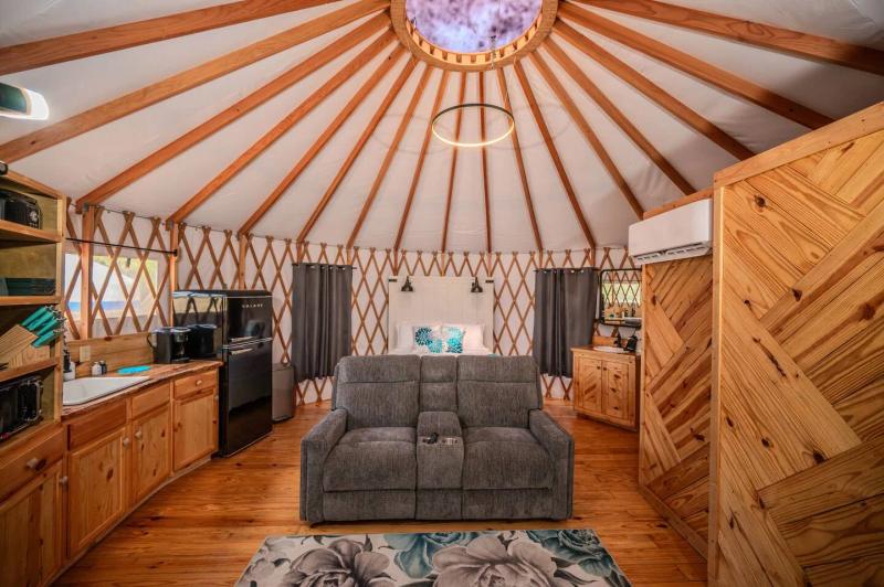 Peacock Yurt — open-plan interior with sofa beneath the clear sky dome.