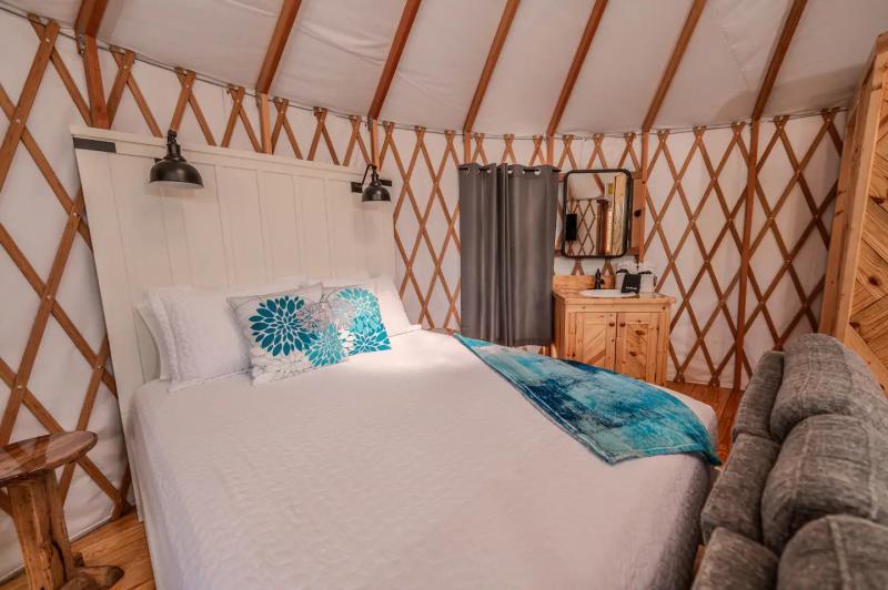 Peacock Yurt — queen bed with turquoise linens beside the living area.