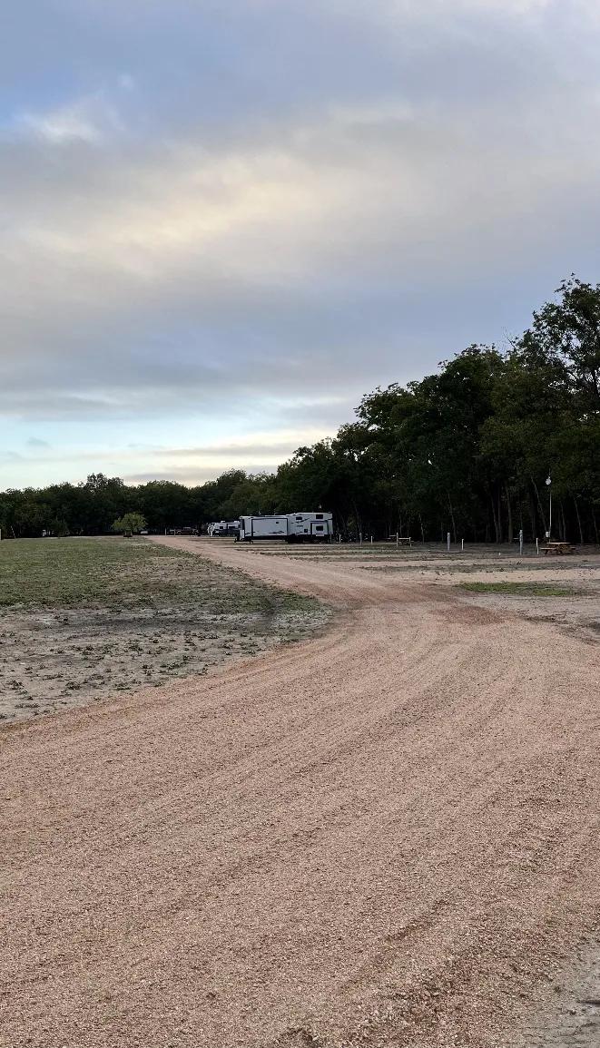 River Yurt Village RV Park — gravel drive running the length of the park at dusk with a rig parked at the far end.
