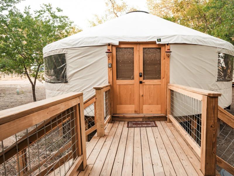 Canvas yurt with double cedar doors at the end of its wooden entry deck