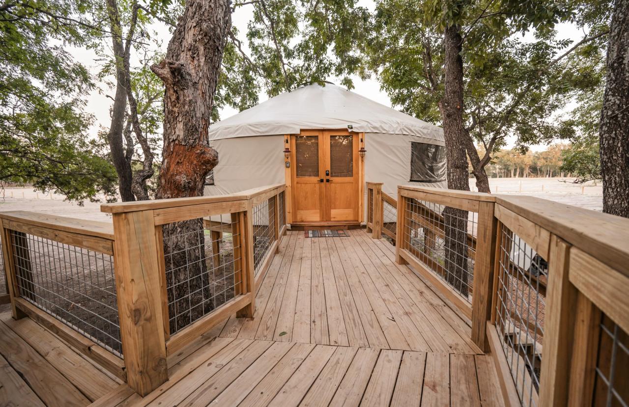 Cedar deck and walkway leading to a canvas yurt framed by live oaks