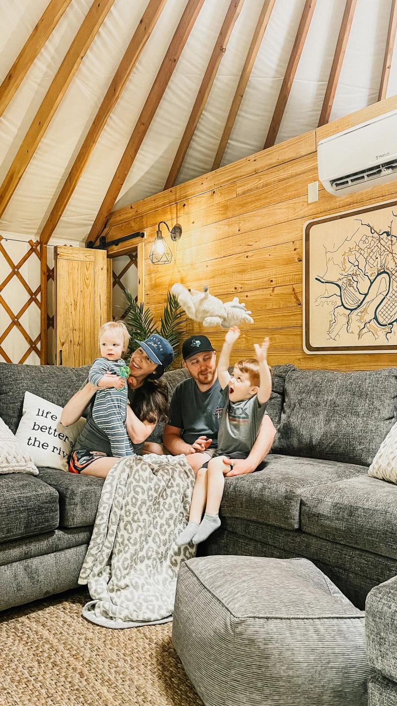 Family stretched out together on the sectional inside a yurt